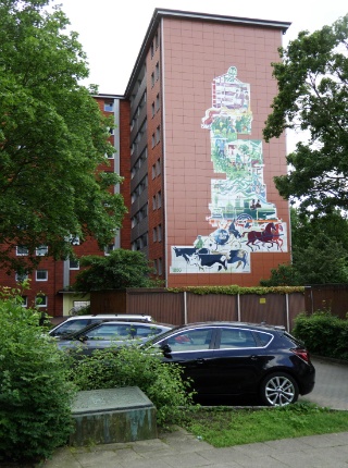 Das Hochhaus mit dem Bild der Geschichte des Siedlungsgebietes Linse in Stellingen-Langenfelde. Vorne der Stein mit der Erklärung.